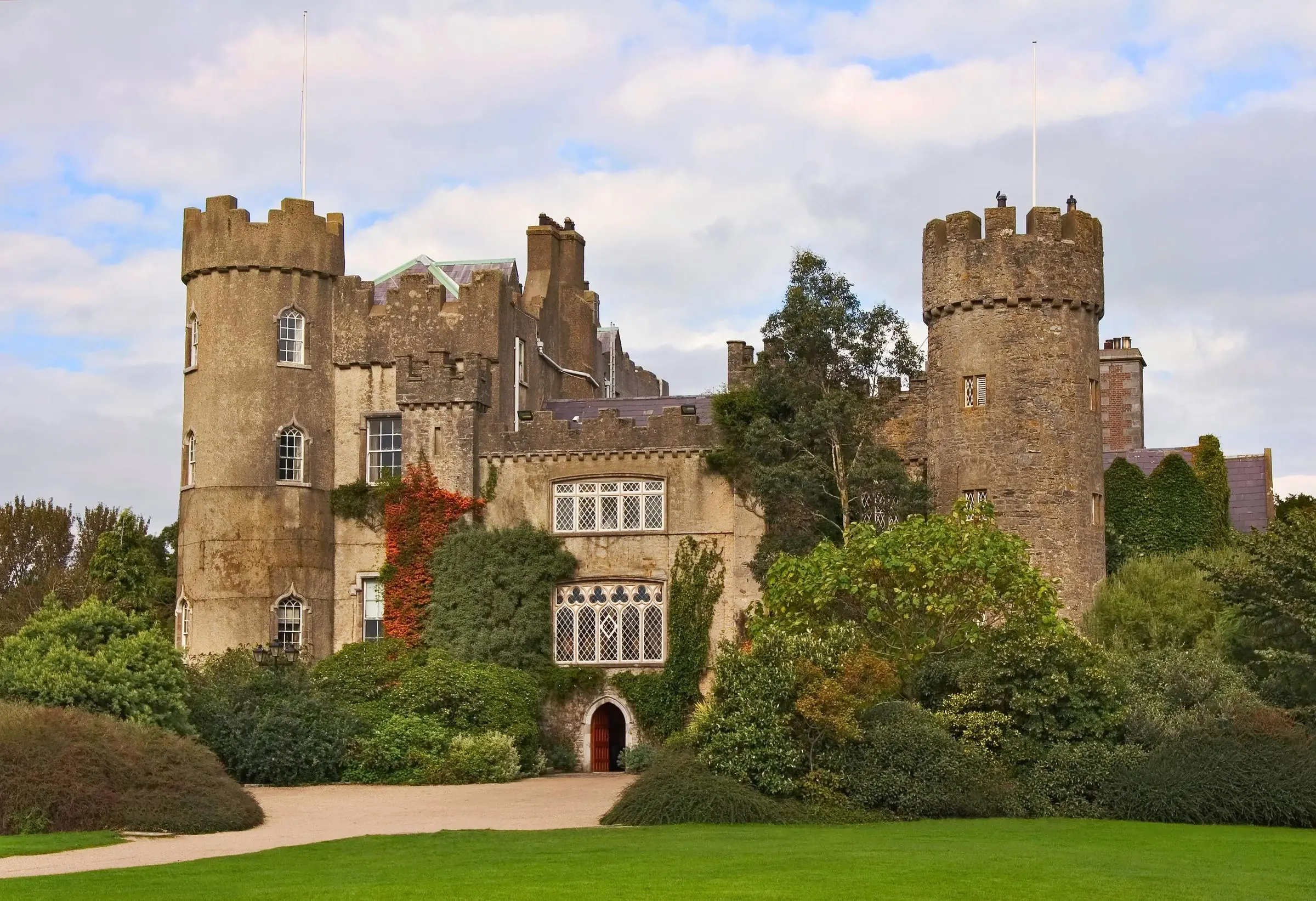 The stone facade and turrets of Malahide Castle surrounded by green lawns